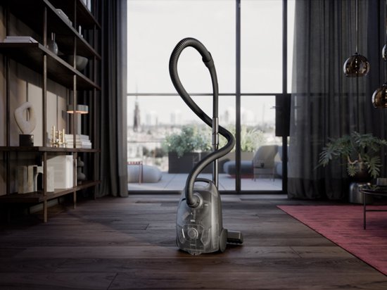 Zwarte AEG stofzuiger in een moderne woonkamer met open haard, plank en uitzicht op de stad.