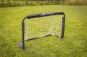 Zwart voetbaldoel met wit net op groen gras