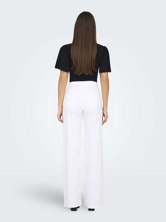 Vrouw met lange bruine haren in zwarte top en witte wide-leg jeans, van achteren gezien.
