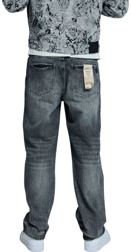 Man met grijze jeans, van achteren gezien. De jeans hebben een losse pasvorm en een label aan de achterkant.