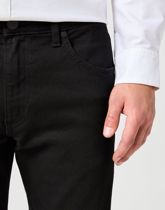 Model draagt zwarte jeans, close-up van de zijkant met zakdetail.