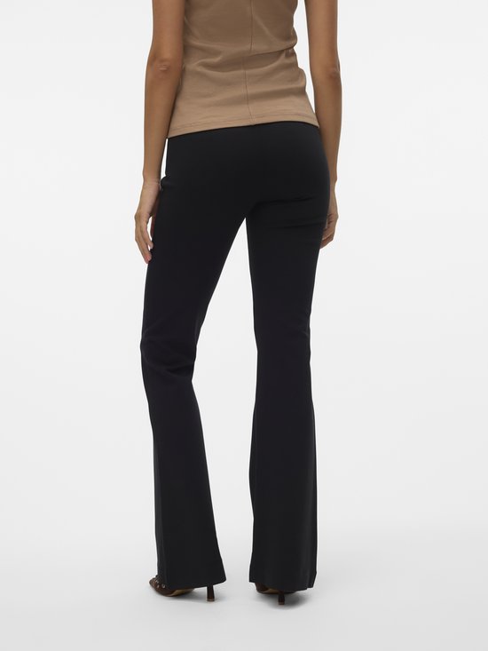 Achterkant van een vrouw in beige top en zwarte flared broek.