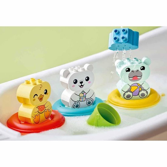 Drie LEGO DUPLO drijvende dieren: een gele eend, een witte beer en een lichtgroen nijlpaard in een wit bad met bubbels. Bovenop valt water uit een blauw blokje.