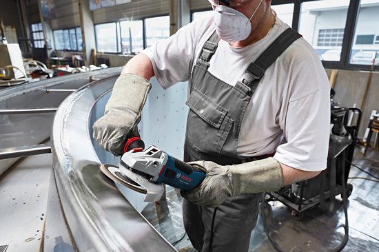 Man met beschermend masker slijpt een metalen rand met een Bosch haakse slijper.