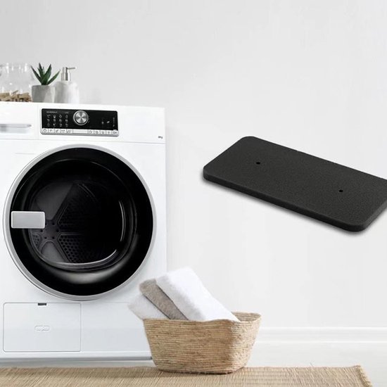 Zwart rechthoekig schuimfilter met twee gaten, gepresenteerd naast een wasmachine en een mand met handdoeken.