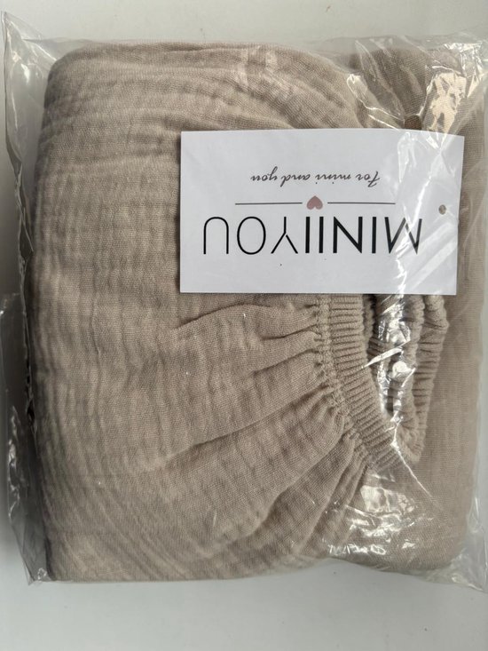 Gevouwen crème hoeslaken in plastic verpakking met label 'MINIIYOU for mom and you'.