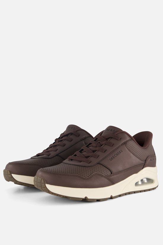 Paar bruine Skechers sneakers met beige zolen en perforaties.