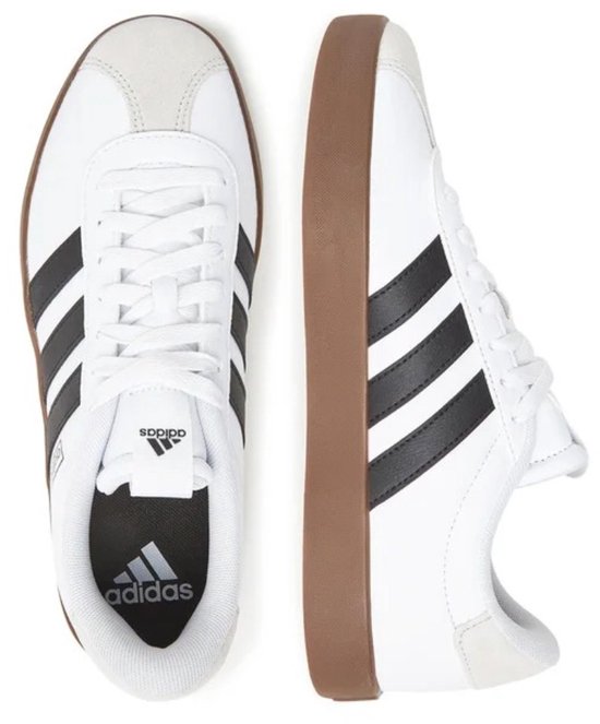 Witte Adidas sneakers met zwarte strepen en bruine zool, van bovenaf gezien.