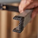 Close-up van een zilverkleurig, metalen zaagbok-onderdeel met zwarte kunststof uiteinden.