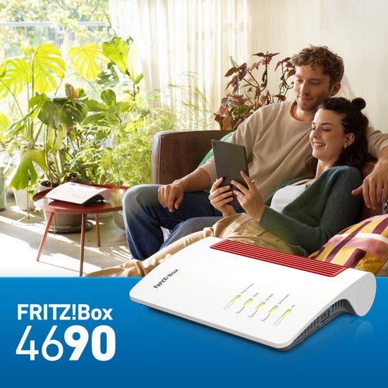 Een man en vrouw zitten op een bank en kijken naar een tablet. Een FRITZ!Box 4690 router staat op de voorgrond.