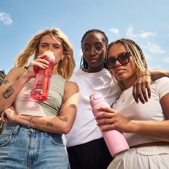 Trois jeunes femmes avec des gourdes Kambukka. L'une tient une gourde rose avec une paille, l'autre une gourde rose texturée.