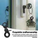 Een zwarte karabijnhaak met schaarclip en D-ring die aan een huissleutel is bevestigd, hangend bij een slot. Een andere zwarte karabijnhaak is aan de linkerkant te zien.