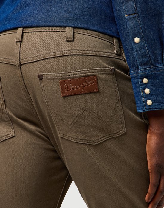 Close-up van de achterkant van een olijfgroene Wrangler broek met bruin leren logo.