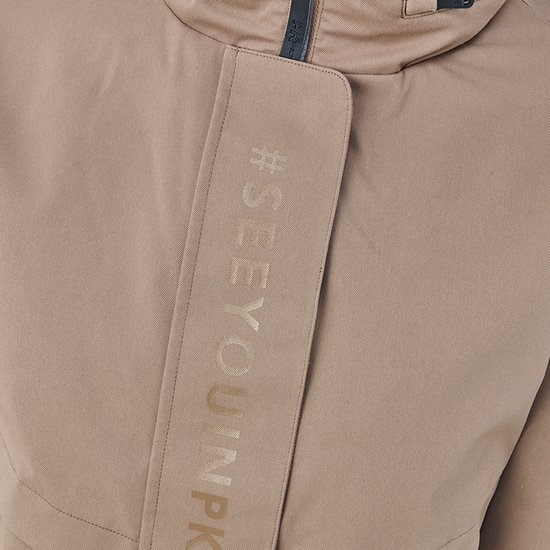 Détail de veste beige pour femme avec texte #SEEYOUNPK sur une bande.