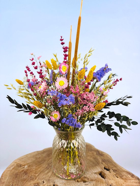 Gedroogd boeket in glazen vaas met roze, paarse en gele bloemen en donkere takjes.