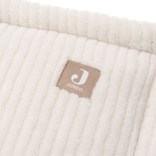 Detailopname van de crème ribbelstof van de Jollein ledikantbumper met het Jollein logo.