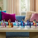 Zeven poppen van de Unicorn Academy, elk op een andere eenhoorn, staan op een tafel.