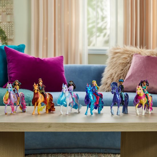 Zeven poppen van de Unicorn Academy, elk op een andere eenhoorn, staan op een tafel.