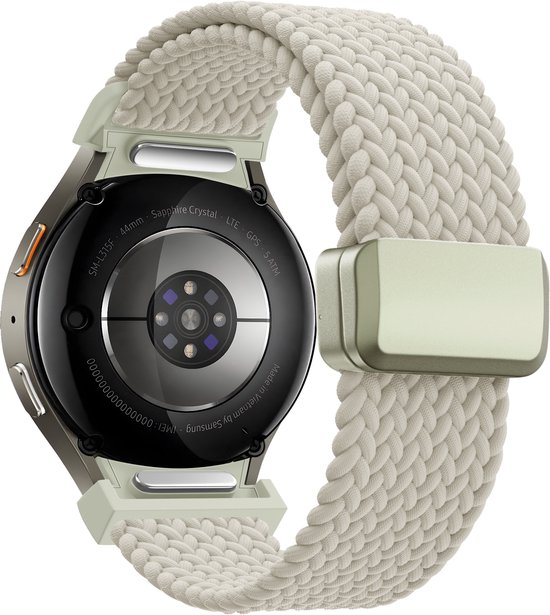 Achterkant van een smartwatch met zilverkleurige behuizing en gebroken witte, geweven band. Tekst 'Samsung'.
