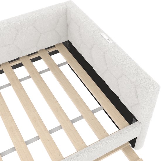 Close-up van de witte slaapbank met hexagonaal patroon, houten lattenbodem en stoffen bekleding.