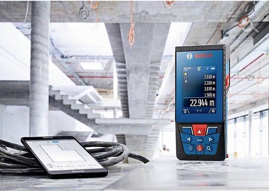 Bosch laser afstandsmeter op een tafel met een smartphone en bouwtekeningen.