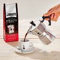 Een Bialetti Moka Express koffiepot die koffie schenkt in een kopje, naast een zak Bialetti 'Perfetto Moka' koffie.