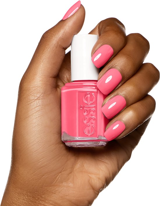 Een hand met donkere huidtint houdt Essie nagellak 'cute as a button' vast, met bijpassende nagels.