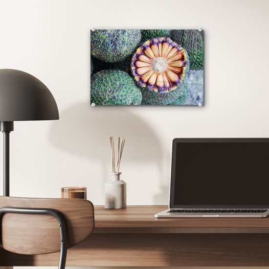 Een glas schilderij van doorgesneden Braziliaans fruit met een opvallende oranje en paarse kern, omringd door groene, geschubde vruchten.
