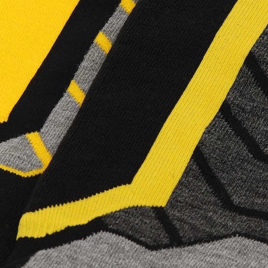 Gros plan de chaussettes de snowboard noires, jaunes et grises avec une texture tissée et un motif rayé.