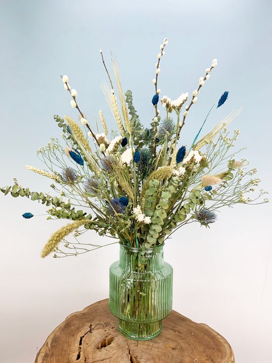 Gedroogd bloemenboeket met blauwe en witte bloemen, tarwe en eucalyptus in een groene geribbelde vaas.