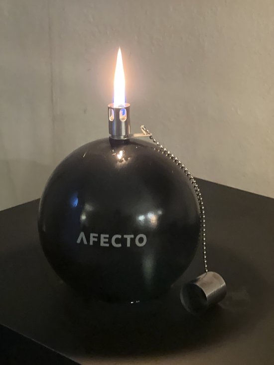 Zwarte, bolvormige olielamp van Afecto met Afecto logo. Met brandende lont en metalen dop aan ketting.