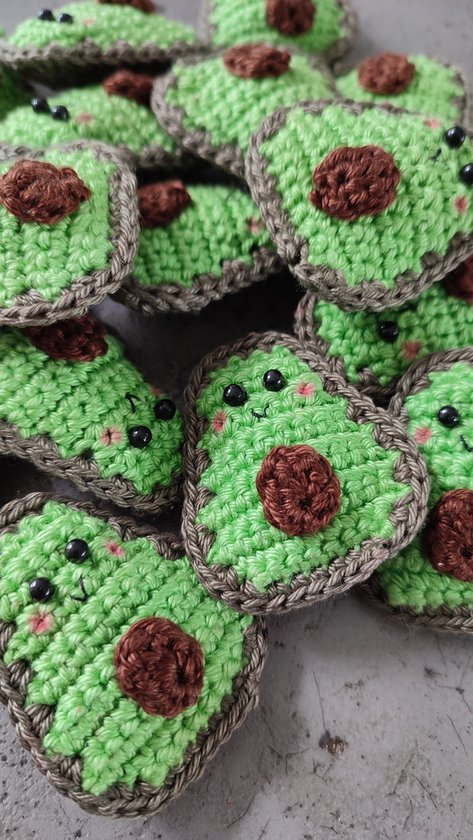 Een stapel gehaakte avocado sleutelhangers met gezichtjes.
