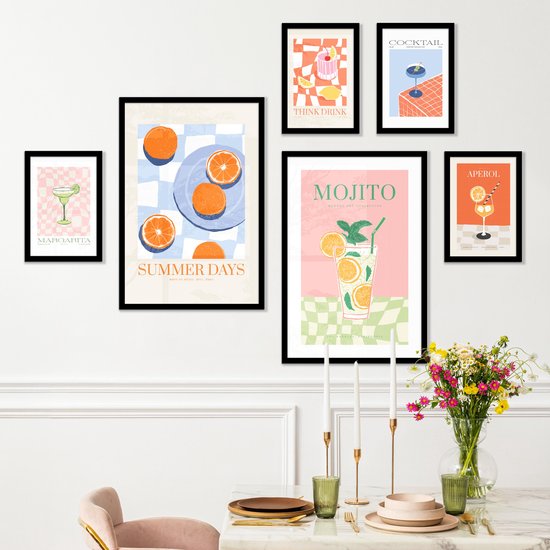 Une salle à manger avec cinq affiches de cocktails et de fruits, accrochées au mur.