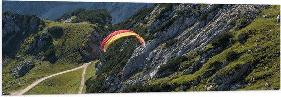 WallClassics - PVC Schuimplaat - Paraglidend door de Bergen en Natuur - 150x50 cm Foto op PVC Schuimplaat (Met Ophangsysteem)