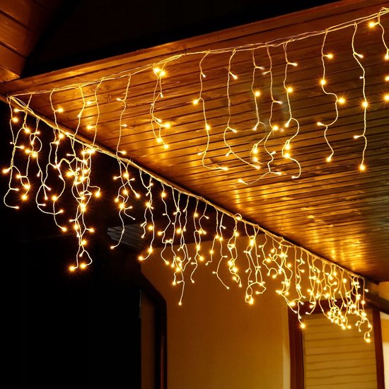 Gele icicle lichtsnoer hangt onder een houten dakrand.