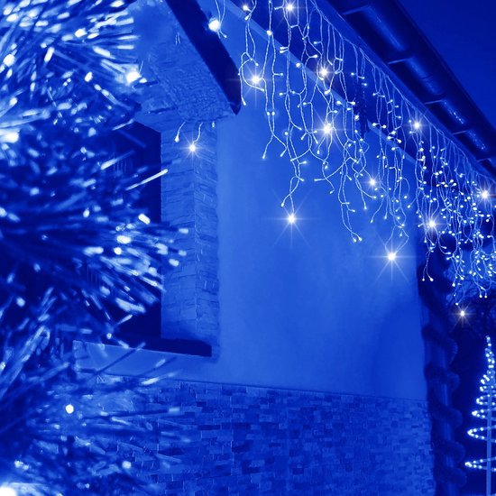 Blauwe LED-ijspegelverlichting opgehangen aan de dakrand van een huis met stenen details, sfeervolle blauwe tint.