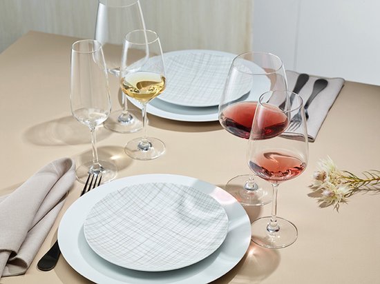 Table dressée avec des verres à vin remplis de vin rouge et blanc, et des flûtes remplies de champagne.