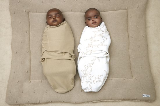 Twee baby's gewikkeld in Meyco inbakerdoeken, één in zandkleur en één met takjesprint.