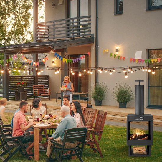 Familie geniet van eten rondom een tafel in de tuin, met een sfeervolle MaxxGarden tuinhaard met vuur.
