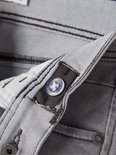 Grijze jeans met donker stiksel en een doorzichtige knoop voor verstelling.