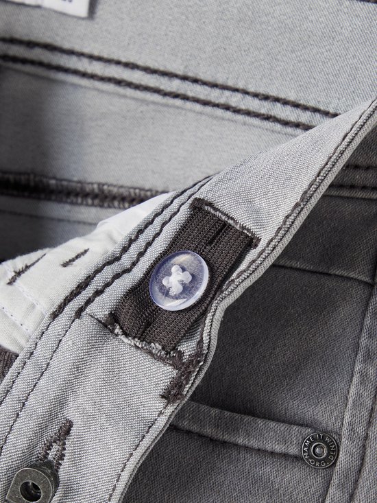 Grijze jeans met donker stiksel en een doorzichtige knoop voor verstelling.