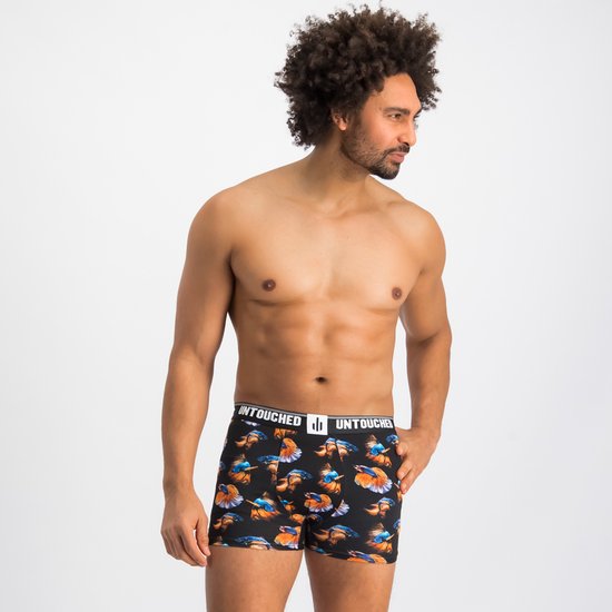 Man naar voren kijkend, draagt een zwarte boxershort met print van exotische vissen in oranje, blauw en geel.