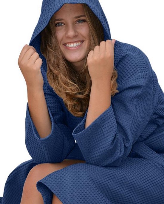 Femme en peignoir gaufré bleu foncé à capuche, mains sur la capuche.