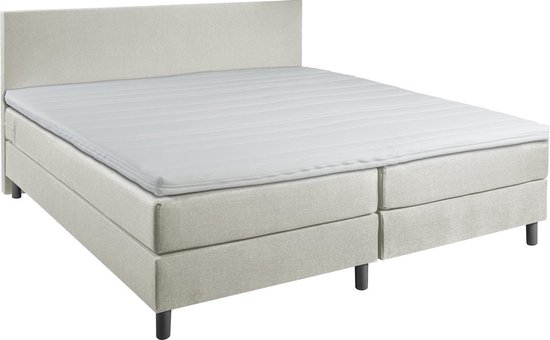 Luxe beige boxspring met gestreept matras en hoofdbord, in een slaapkamerinterieur.
