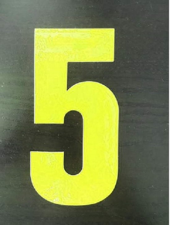 Gele cijfersticker '5' met een reflecterend oppervlak op een zwarte achtergrond.