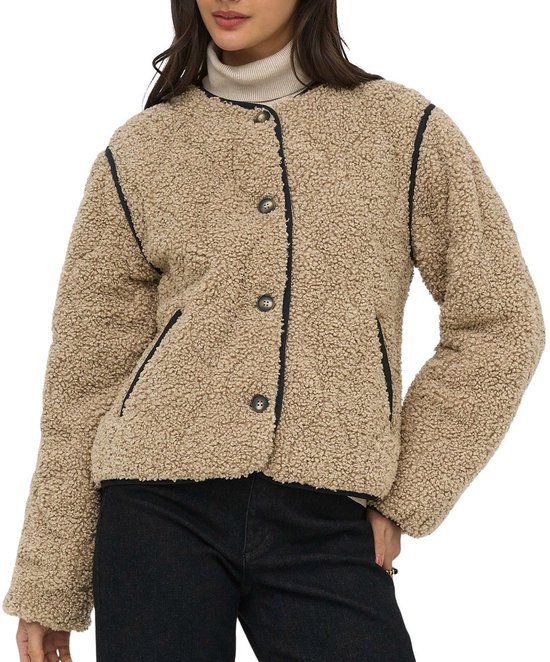 Model van voren, draagt een beige teddy jas met zwarte bies, knopen en zwarte jeans.