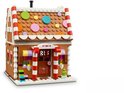 Een LEGO peperkoekhuis met bruine muren, witte daken met kerstdecoratie en gekleurde ronde versieringen.