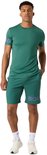 Man in groen sportshirt met korte mouwen en short, met paarse tekst op de mouw en short.