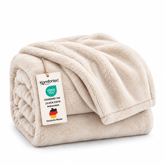 Opgevouwen crèmekleurige fleece deken van Komfortec met OEKO-TEX label.