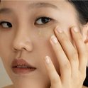 Een vrouw brengt Beauty of Joseon Ginseng + Retinol Revive oogserum aan onder haar oog.